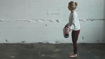 Woman unrolling an anti-slip suede top natural rubber yoga mat on a studio floor.